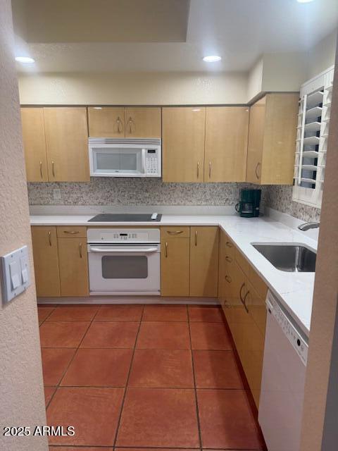 kitchen featuring white appliances, light brown cabinetry, sink, and decorative backsplash