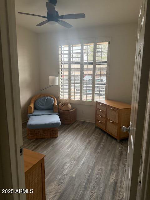 living area with dark wood-type flooring and ceiling fan