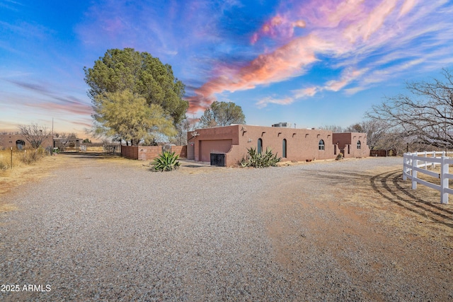 pueblo-style house with a gate, fence, an attached garage, and stucco siding