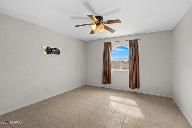 empty room with a ceiling fan and baseboards