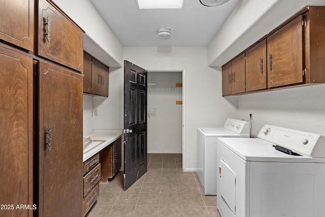 clothes washing area with light tile patterned floors, independent washer and dryer, cabinet space, and baseboards