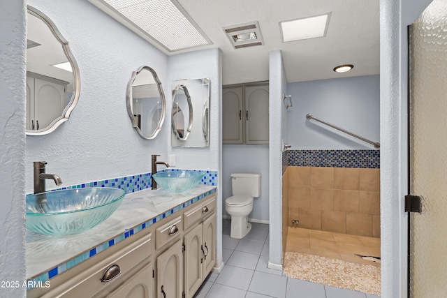 full bathroom featuring toilet, double vanity, a sink, and tile patterned floors