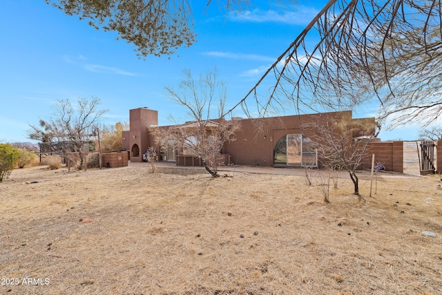 exterior space with a gate, fence, and stucco siding