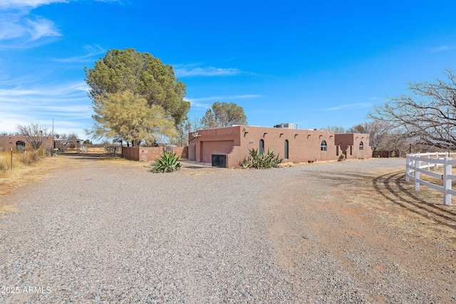 adobe home featuring a gate, fence, and stucco siding