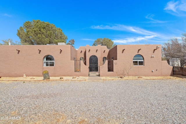 adobe home with fence private yard, a gate, and stucco siding