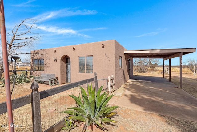 pueblo revival-style home featuring fence and stucco siding