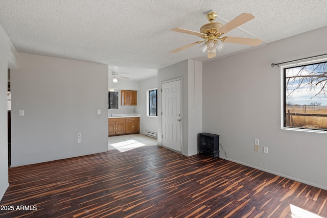 empty room featuring a baseboard radiator, a textured ceiling, ceiling fan, and wood finished floors