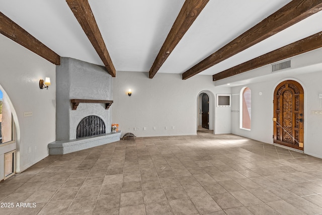 unfurnished living room featuring arched walkways, a large fireplace, visible vents, beam ceiling, and tile patterned floors