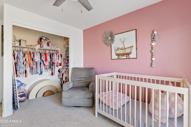 carpeted bedroom featuring ceiling fan, a closet, and a crib