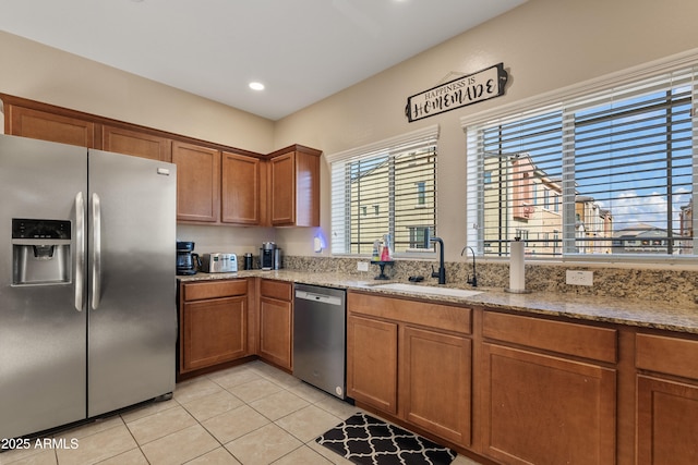 kitchen with stone counters, light tile patterned flooring, appliances with stainless steel finishes, and sink