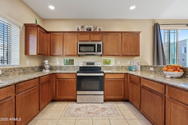 kitchen with appliances with stainless steel finishes, light stone countertops, and light tile patterned floors