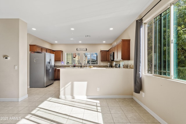 kitchen featuring appliances with stainless steel finishes, kitchen peninsula, light stone countertops, and light tile patterned floors