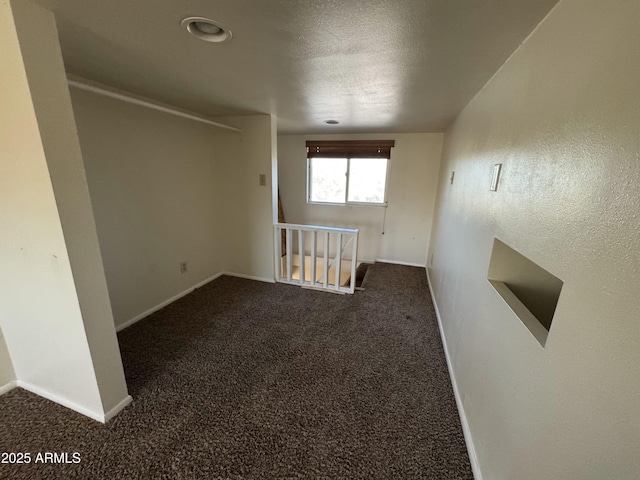 spare room with a textured ceiling and dark colored carpet