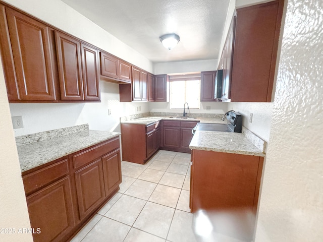 kitchen featuring stainless steel range with electric cooktop, light tile patterned flooring, light stone countertops, a textured ceiling, and sink