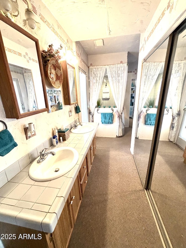 full bath with ensuite bathroom, double vanity, and a sink