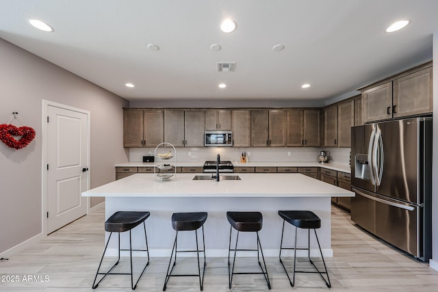 kitchen with a sink, stainless steel appliances, visible vents, and a breakfast bar