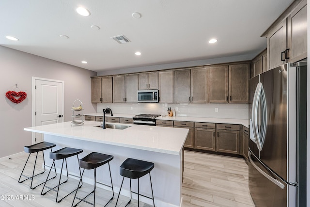 kitchen with a sink, visible vents, appliances with stainless steel finishes, and a breakfast bar area