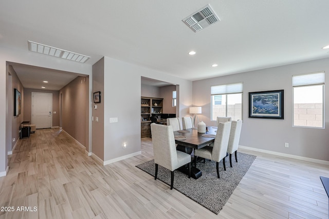 dining space with baseboards, visible vents, and light wood finished floors