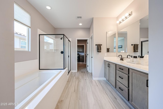 full bathroom with visible vents, double vanity, a stall shower, a sink, and a bath