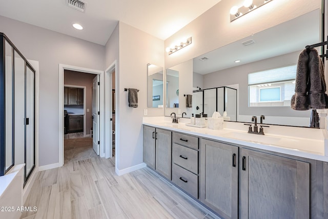 bathroom with baseboards, visible vents, double vanity, a stall shower, and a sink