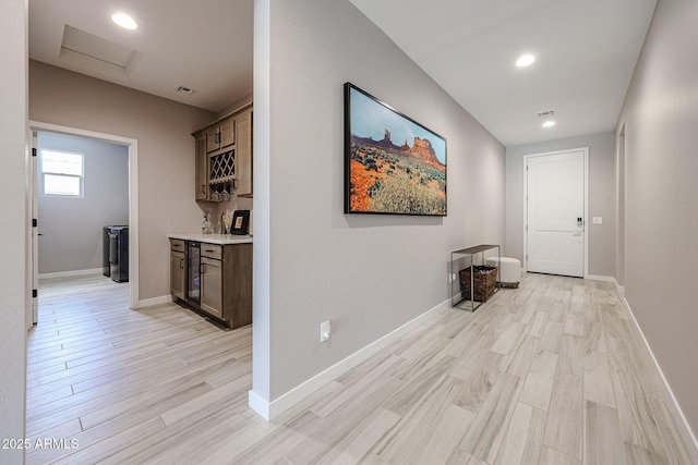 hall featuring baseboards, attic access, and light wood-style floors