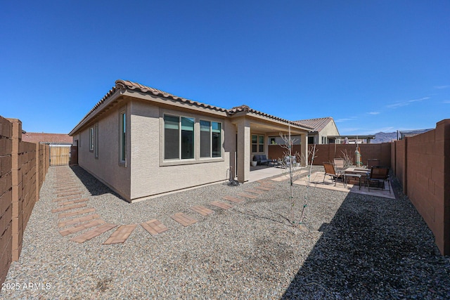 back of house with a patio, a tiled roof, a fenced backyard, and stucco siding