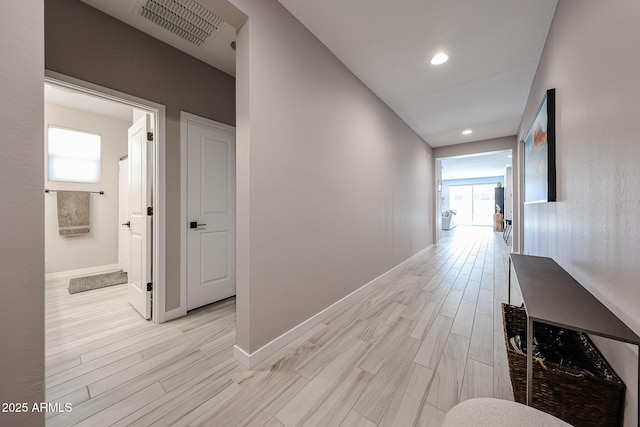 hallway with visible vents, plenty of natural light, baseboards, and light wood-style floors