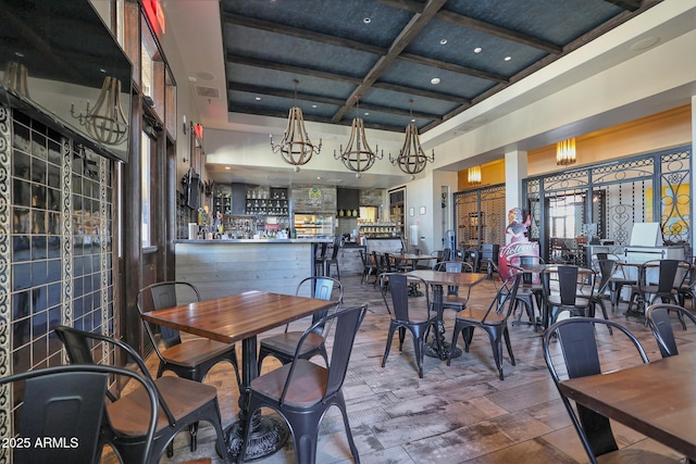 dining space with wood finished floors, visible vents, coffered ceiling, beam ceiling, and a high ceiling