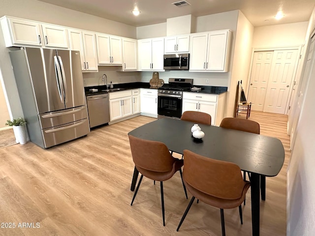 kitchen with sink, light hardwood / wood-style flooring, stainless steel appliances, and white cabinets