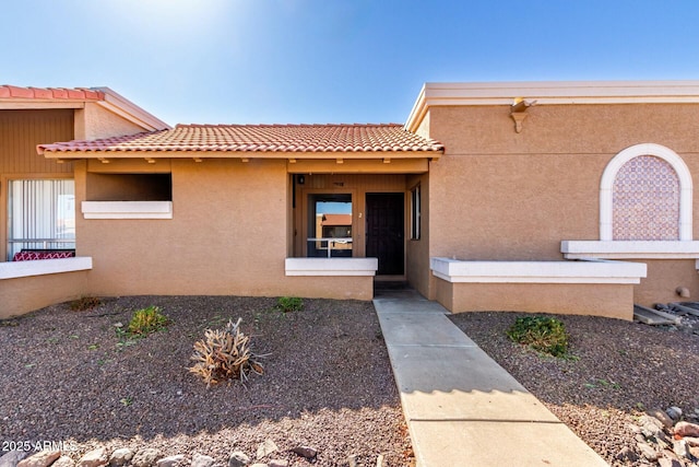 doorway to property with a tile roof and stucco siding