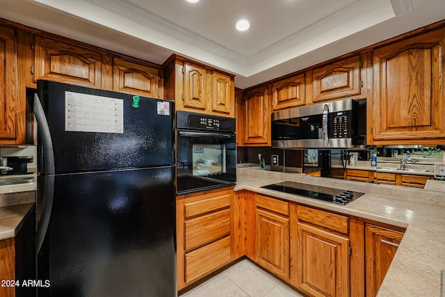 kitchen with light tile floors, sink, a tray ceiling, crown molding, and black appliances