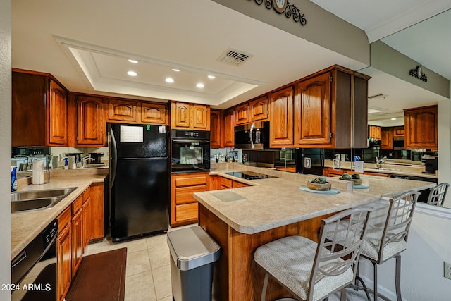 kitchen with light tile floors, a breakfast bar, black appliances, and a raised ceiling