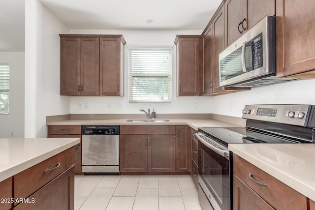 kitchen featuring a sink, light tile patterned floors, stainless steel appliances, and light countertops