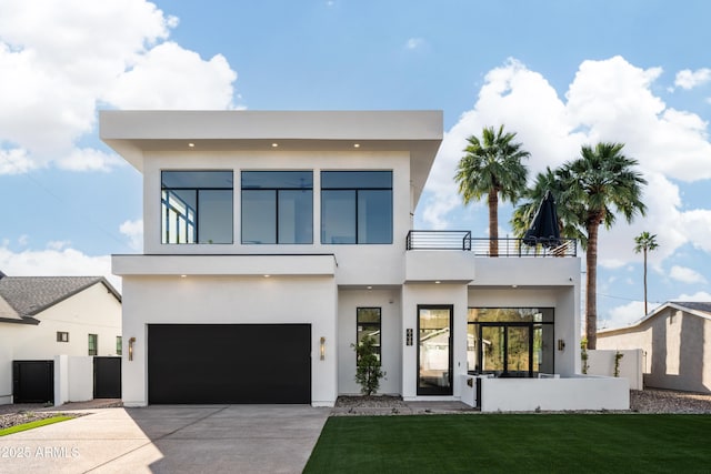 contemporary home featuring driveway, a garage, a balcony, fence, and stucco siding