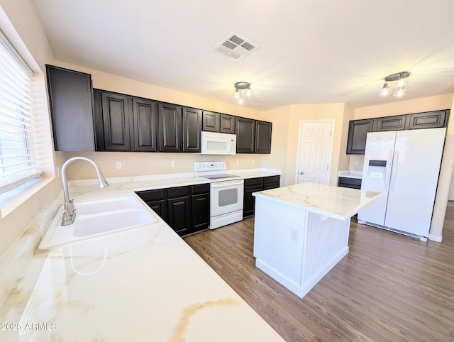 22523 W Pima St, Buckeye, AZ 85326 - kitchen with white appliances, a kitchen island, wood finished floors, light stone counters, and dark cabinets