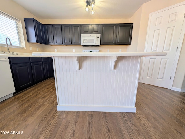 22523 W Pima St, Buckeye, AZ 85326 - kitchen with white appliances, dark wood finished floors, a breakfast bar, and light countertops