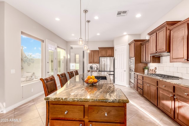 kitchen featuring sink, decorative light fixtures, stainless steel appliances, a kitchen island with sink, and decorative backsplash