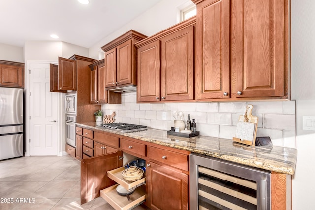 kitchen featuring appliances with stainless steel finishes, wine cooler, decorative backsplash, light tile patterned floors, and light stone counters