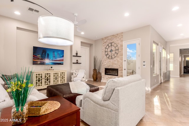 tiled living room with ceiling fan and a fireplace