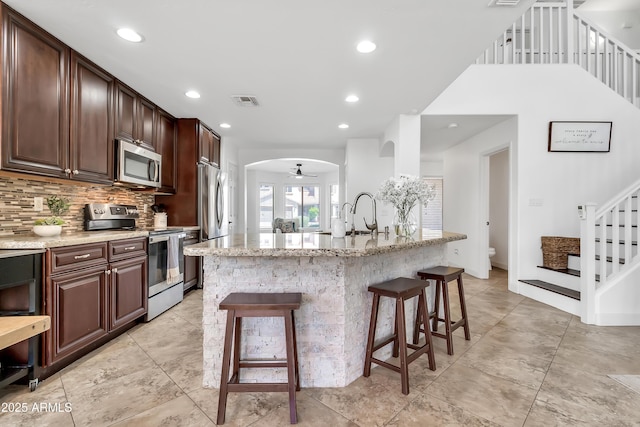 21167 E Aspen Valley Dr, Queen Creek, AZ 85142 - kitchen featuring stainless steel appliances, a kitchen bar, light stone countertops, tasteful backsplash, and recessed lighting