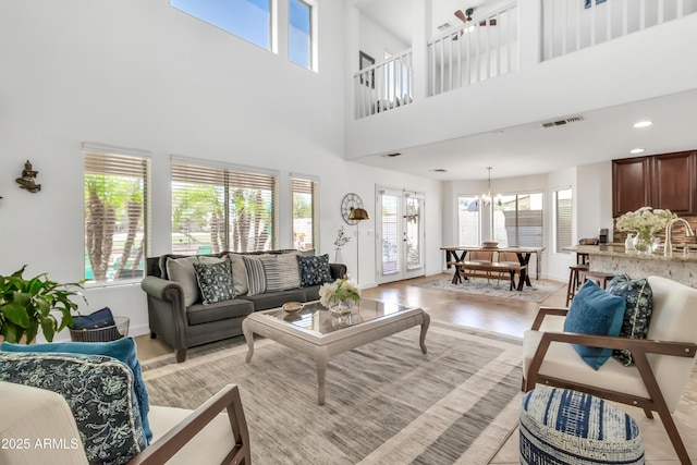21167 E Aspen Valley Dr, Queen Creek, AZ 85142 - living area featuring baseboards, a towering ceiling, a chandelier, and light wood-type flooring