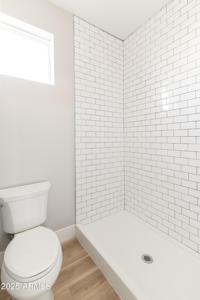 bathroom featuring toilet, tiled shower, and hardwood / wood-style flooring