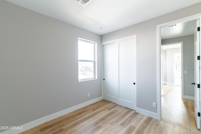 unfurnished bedroom with light hardwood / wood-style flooring and a closet