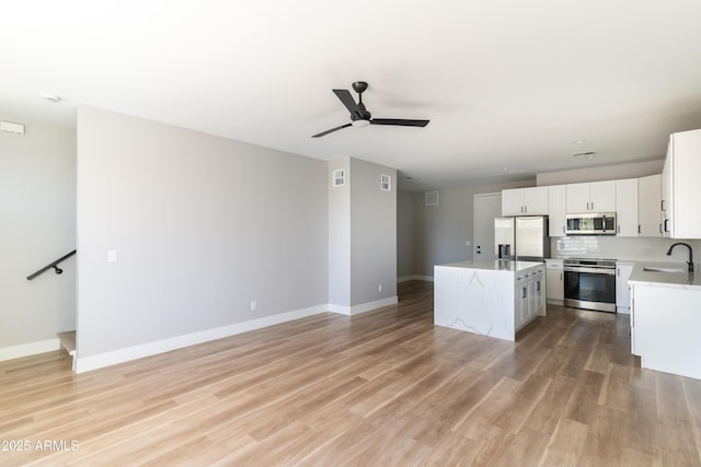 kitchen with white cabinets, a kitchen island, stainless steel appliances, decorative backsplash, and sink