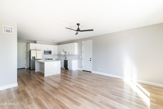 kitchen with a kitchen island, white cabinetry, stainless steel appliances, decorative backsplash, and ceiling fan