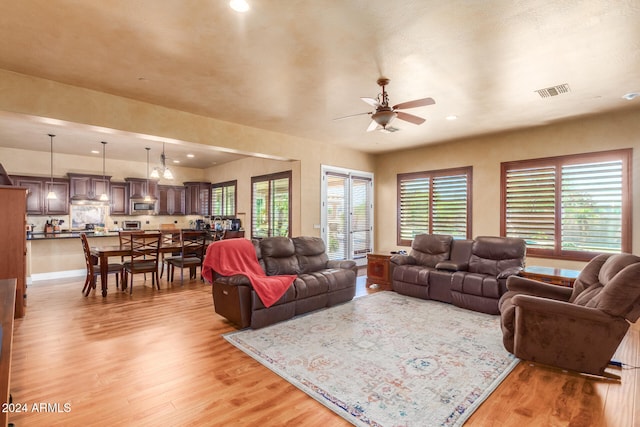 living room featuring a wealth of natural light, light wood-type flooring, and ceiling fan