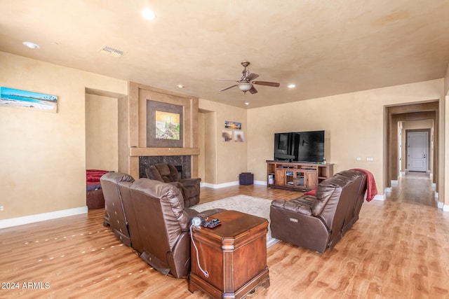 living room with a premium fireplace, light hardwood / wood-style flooring, and ceiling fan