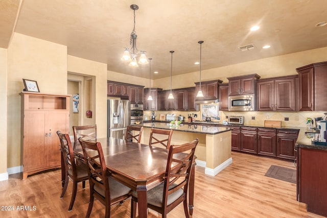 dining space with light hardwood / wood-style floors and a chandelier