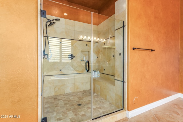 bathroom with a shower with door and tile patterned floors