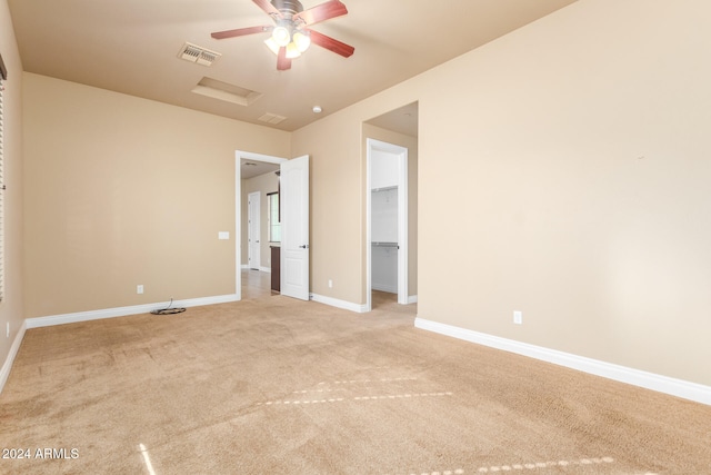 unfurnished bedroom with a spacious closet, carpet, a closet, and ceiling fan